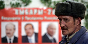 Un hombre bielorruso, junto a un cartel con los retratos de los candidatos a la presidencia del país, durante las elecciones presidenciales que se celebran hoy domingo 19 de marzo. (EFE)