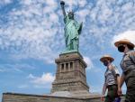 Dos oficiales del servicio de Parques Nacionales de EE UU, junto la Estatua de la Libertad, en Nueva York, tras la reapertura de la isla donde se encuentra el monumento, despu&eacute;s de haber estado cuatro meses cerrada por la pandemia del coronavirus.