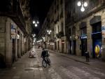 Un repartidor de comida a domicilio circula con su bicicleta por una calle vac&iacute;a del centro de Barcelona, la primera noche con toque de queda en la ciudad.