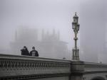 Dos hombres con mascarillas cruzan el puente de Westminster en Londres.