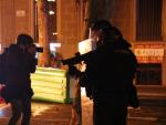 Un periodista fotograf&iacute;a a un agente de Mossos d'Esquadra con una pistola de foam durante las protestas por el encarcelamiento de Hasel en Barcelona.