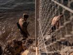 Un soldado del ej&eacute;rcito ayuda a un inmigrante a su llegada a la playa de El Tarajal en Ceuta