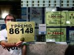 El propietario de la administración de la Estación de Atocha, en Madrid, muestra el 86148 que ha sido agraciado con el primer premio de la Lotería de Navidad 2021.