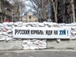 Una pancarta en Odesa pegada a un puesto de control reforzado con bloques de hormig&oacute;n y sacos de arena