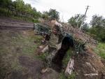 El soldado ucraniano 'Den' sale de una trinchera en un bosque de Ucrania.