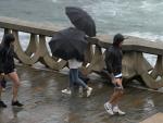 Varias personas con paraguas caminan por el Paseo Mar&iacute;timo de La Coru&ntilde;a, Galicia.