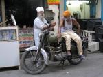 Un hombre sobre una motocicleta habla con otro en Nueva Delhi, India.