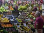 Un hombre observa el g&eacute;nero en un puesto de frutas en el mercado sevillano de Triana.