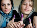 Las primeras elecciones legislativas de Irak arrancan con fuego de mortero sobre Bagdad. En la imagen, unas mujeres que acaban de votar muestran sus dedos manchados de tinta.