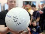 Un visitante muestra un bal&oacute;n de f&uacute;tbol firmado por el presidente fundador de Microsoft Bill Gates.