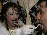 Nartis Adeiel Fadhil (I) y Kadhim Qasim Mohammed toma el tradicional pastel durante la boda masiva celebrada en Bagdad (REUTERS)