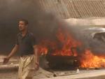 Un hombre pasa delante de uno de los coches incendiados por la explosi&oacute;n de un cami&oacute;n bomba en la ciudad de Kirkuk.