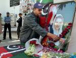 Un guardia de seguridad del partido de Bhutto coloca flores ante un retrato de la l&iacute;der opositora asesinada. (EFE)