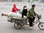 Una pareja de chinos transporta un jarr&oacute;n por las calles de Pek&iacute;n.