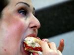 Una mujer saborea una hamburguesa.