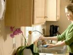 Una mujer friega los platos en una cocina.