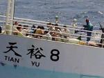 Dos piratas somal&iacute;es amenazan con sus armas a los tripulantes del barco pesquero chino 'Tian Yu 8', secuestrado en el &Iacute;ndico. (EFE)