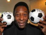 El ex futbolista brasile&ntilde;o Pel&eacute; posando con dos balones de f&uacute;tbol en Madrid.