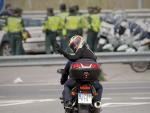 Un motorista hace el signo de la victoria cerca de los agentes de la Guardia Civil que vigilan los accesos al circuito de Jerez de la Frontera (C&aacute;diz). Este fin de semana se celebra el Gran Premio de Espa&ntilde;a de Motociclismo.
