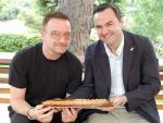 El cantante Bono recibe una torta de Llavaneres del alcalde de la localidad, Bernat Graupera.