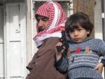Un ni&ntilde;o, junto a su padre, juega con una pistola de pl&aacute;stico en el campamento de refugiados palestinos de Kalandia.