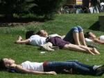 Un grupo de j&oacute;venes tomando el sol en el c&eacute;sped de un parque.