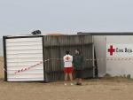 Dos voluntarios de Cruz Roja, junto a la caseta que ha sido levantada por un tornado durante las trombas de agua en la playa de Burriana.