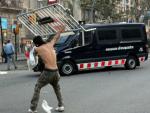 Un manifestante lanza una valla met&aacute;lica contra un furg&oacute;n de los Mossos D'Esquadra durante la manifestaci&oacute;n celebrada con motivo de la huelga general en Barcelona, ciudad que ha sido escenario de graves altercados.