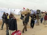 Trabajadores sudaneses que huyeron de Libia, transportan sus pertenencias en el campo de refugiados instalado junto a la frontera de Ras el Jedir (T&uacute;nez).