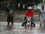 Varios hombres transitan por una calle inundada tras las lluvias de la tormenta tropical 'Emily' a su paso por San Crist&oacute;bal (Rep&uacute;blica Dominicana.