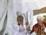 Un sacerdote protege de la lluvia y el viento al papa Benedicto XVI durante la vigilia con los j&oacute;venes que el Santo Padre ha celebrado en el aer&oacute;dromo de Cuatro Vientos.