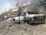 Varias personas observan el lugar de la explosi&oacute;n de un coche bomba frente al Ministerio de Educaci&oacute;n en Mogadiscio (Somalia).