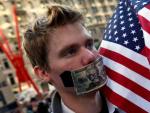 Uno de los manifestantes de Nueva York se tapa la boca con un billete de d&oacute;lar.