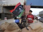 Un rebelde libio con una camiseta del club de f&uacute;tbol AC Milan en un punto de control hecho con contenedores entre Tr&iacute;poli y Misrata, en Libia.