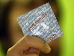 Un joven sosteniendo un preservativo.