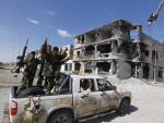 Un grupo de rebeldes celebra la ca&iacute;da de Sirte, junto a un edificio en ruinas.
