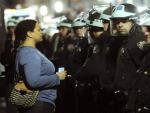 Una mujer mira fijamente a los polic&iacute;as durante el desalojo de los 'indignados' de Nueva York del movimiento 'Occupy Wall Street' que acamparon en el parque Zuccotti.