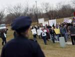 Un polic&iacute;a observa c&oacute;mo un grupo de manifestantes avanza hacia la oficina en Iowa de la candidata republicana Michele Bachmann.