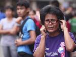 Una mujer intenta llamar desde el m&oacute;vil en Cebu (Filipinas) tras un terremoto de 6,7 en la escala Ritcher.