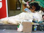 Un mendigo duerme pr&oacute;ximo a un comercio.