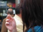 Una mujer se fuma un cigarro en una terraza de bar