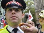 Una manifestante de Occupy London ofrece comida a un polic&iacute;a.
