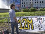 Dos j&oacute;venes en la Plaza de Catalu&ntilde;a sostienen una pancarta con un 12-M escrito en ella, el d&iacute;a de inicio oficial de los actos conmemorativos del aniversario del movimiento 15-M.