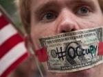 Un manifestante de 'Occupy Wall Street' se tapa la boca con un billete de d&oacute;lar en el parque Zuccotti de Nueva York, donde hace un a&ntilde;o surgi&oacute; el movimiento.