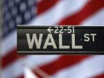 Imagen de un cartel de Wall Street con la bandera estadounidense de fondo.