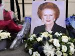 Varias personas depositan flores y art&iacute;culos relacionados con Margaret Thatcher en la puerta de su casa.
