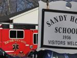 Coches de polic&iacute;a y bomberos delante de un letrero de la escuela Sandy Hook en Newtown (Connecticut, EE UU), donde ha tenido lugar el tiroteo.