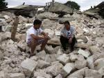 Dos hombres permanecen sentados entre los escombros de la iglesia de Nuestra Se&ntilde;ora de la Luz, destruida por el terremoto de Bohol (Filipinas).