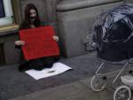 Una mujer pasa con un carrito de beb&eacute; junto a una activista que sostiene un cartel que dice &quot;dadme una ayuda para ir a Londres a abortar&quot;, como protesta contra la nueva ley del aborto del Gobierno del PP.