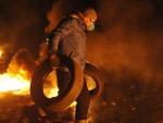 Un manifestante lleva dos llantas para iniciar una nueva hoguera, durante una tregua temporal con la polic&iacute;a en las protestas en Kiev (Ucrania).